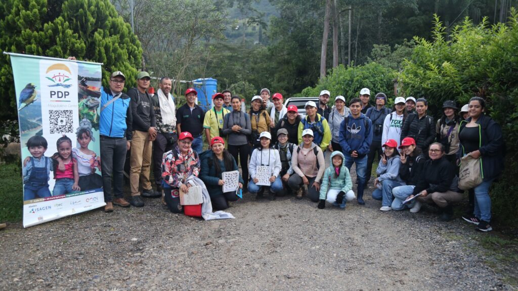 Grupo de participantes posa junto a la imagen institucional del PDPMC al inicio del recorrido