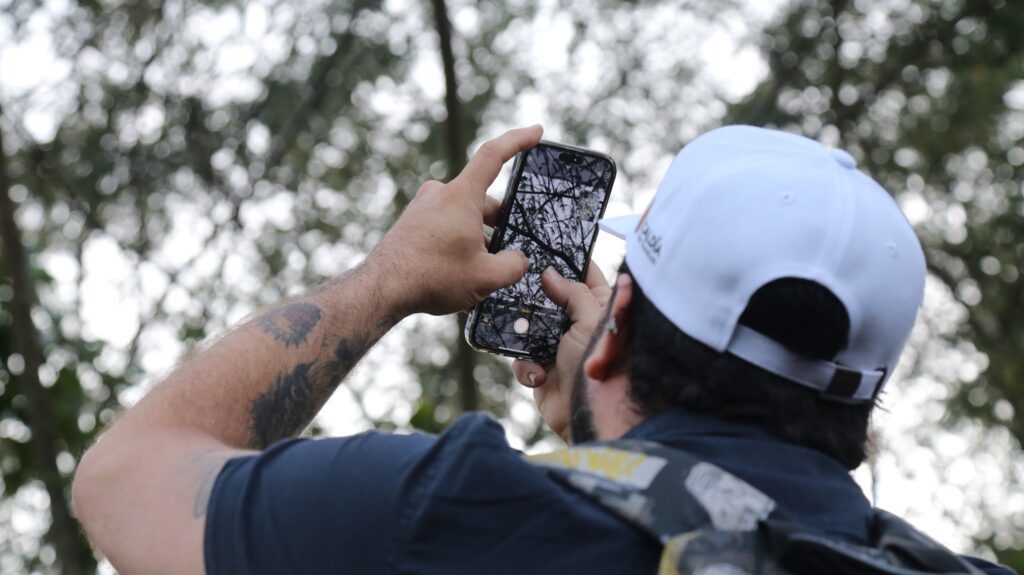 Participante fotografía un ave en las ramas con su teléfono